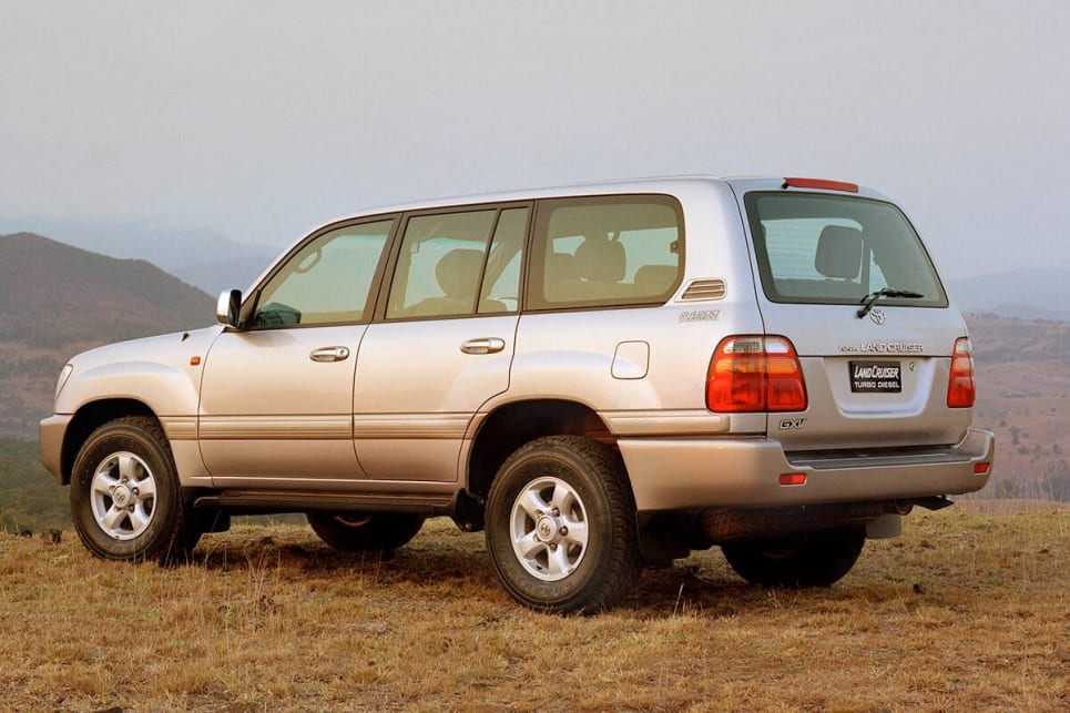 4x4 Toyota Prado rental vehicle with a roof rack driving on a clean tarmac highway winding through the iconic lush green terraced rolling hills of Rwanda under a clear blue sky
